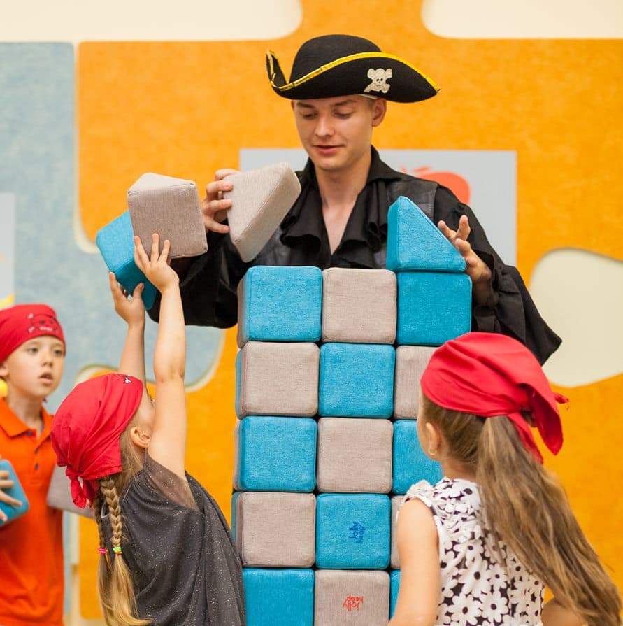 Children in pirate bandanas building a tower from JollyHeap blocks during themed play