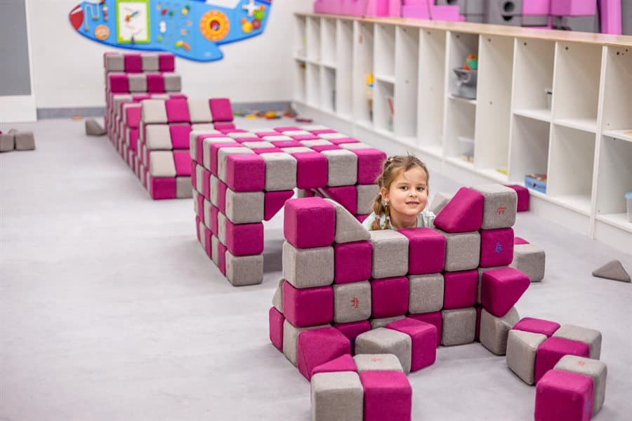 A girl looking out from behind a structure she built from JollyHeap blocks