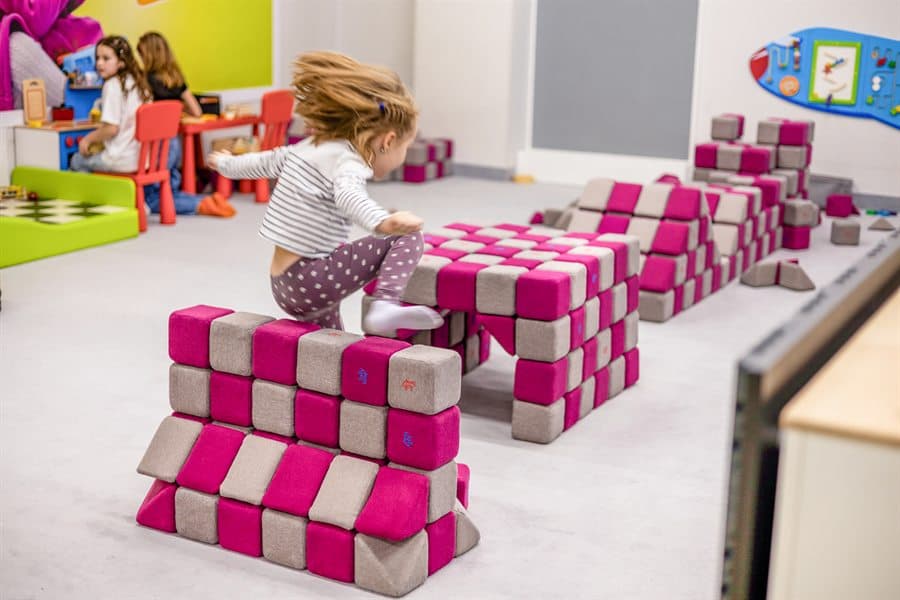 A child jumping over an obstacle course built from JollyHeap blocks in a room