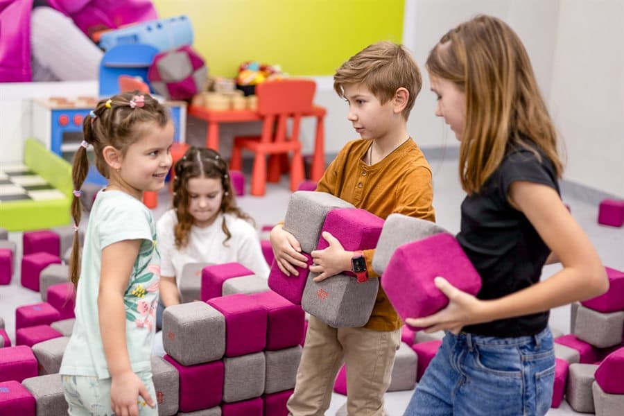Four children carrying JollyHeap blocks and agreeing what to build next