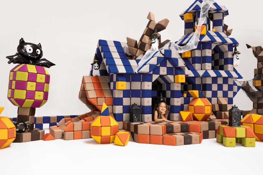 A girl in a black hat looking out of the window of a big JollyHeap block set: a haunted house with a bat and cobwebs