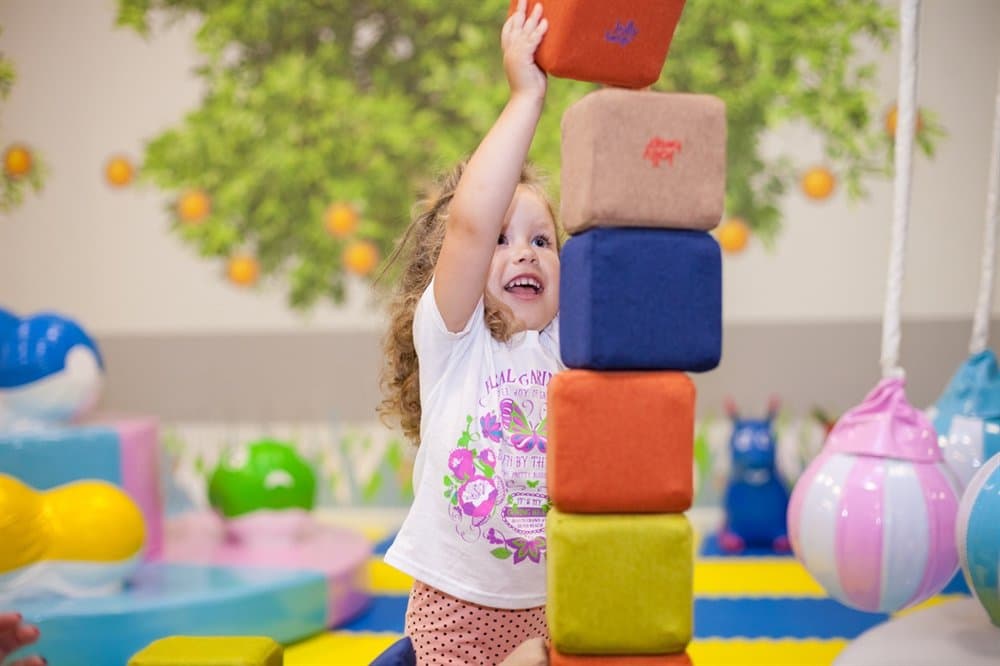 A girl adding a block to the top of a tall tower