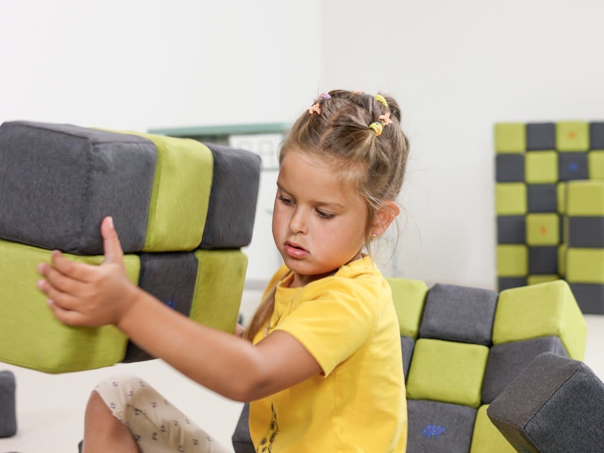 A girl carrying two large blocks