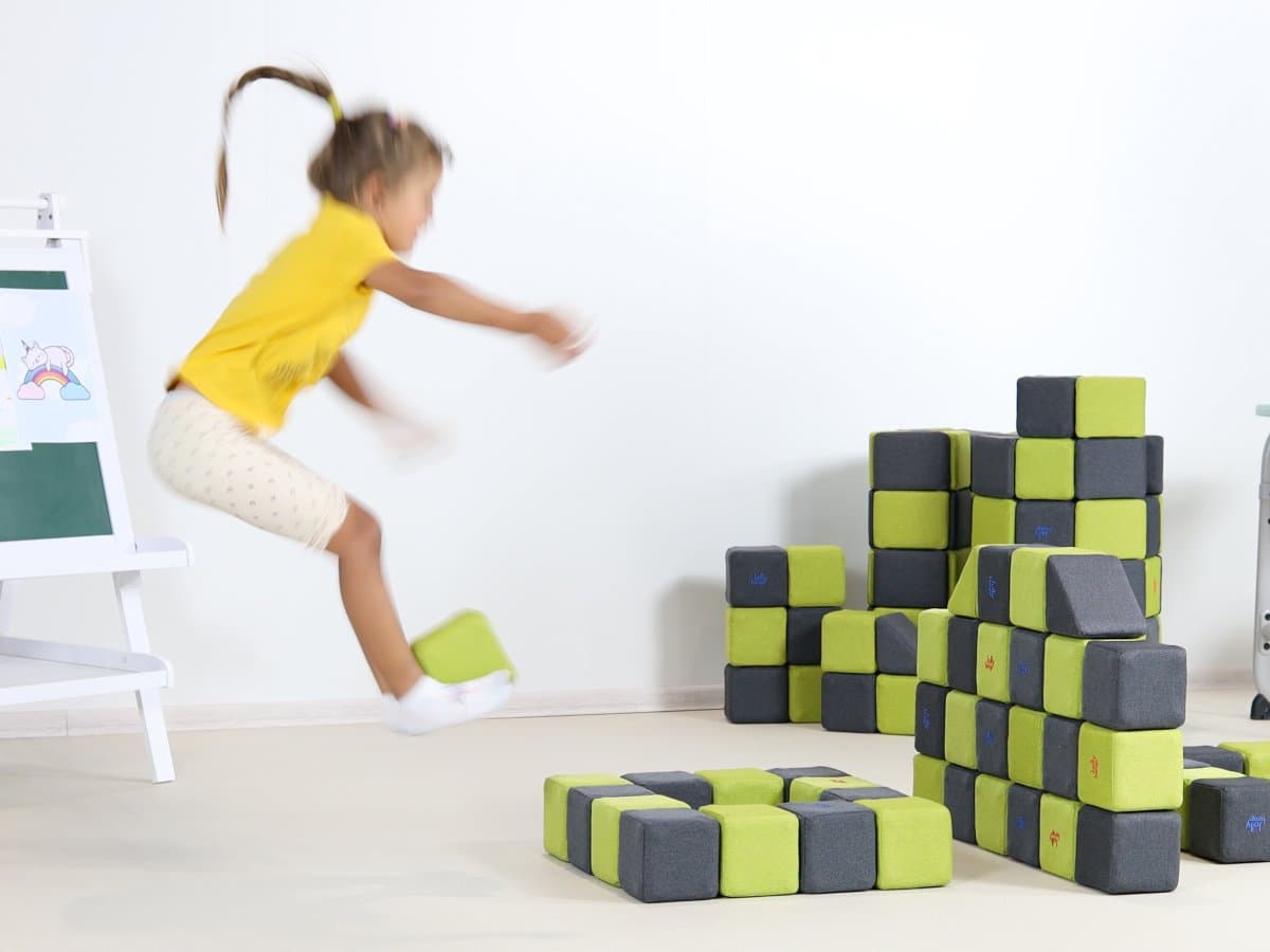 A girl jumping next to a wall of blocks