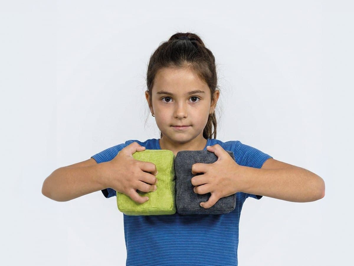 A girl pressing two JollyHeap blocks, one green and one grey, together in her hands